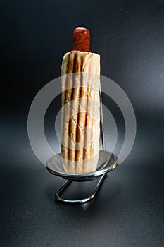French hot dog on a black background. Fast food bakery product. production. Vertical photo