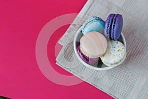 French macarons in cup. Sweet colorful bisquits. Top view. Hot pink background. Table cloth.