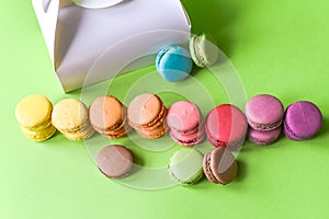 French macarons and a white box over a green background