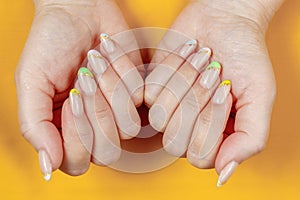 French manicure in green, yellow, purple on a solid background. Nail art on women's nails.