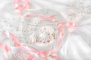 French meringue cookies for wedding background with pearls, pink and white satin ribbons and lace