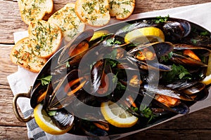 French mussels with lemon, parsley and garlic close-up in a copper pot and toast. horizontal top view