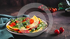 French omelette filled with cherry tomatoes and arugula on a plate on the table web banner