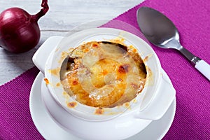 French onion gratin soup in a white pot, close-up