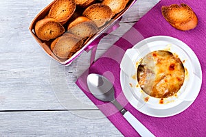 French onion gratin soup in a white pot, close-up