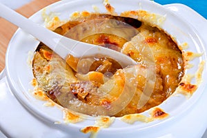 French onion gratin soup in a white pot, close-up