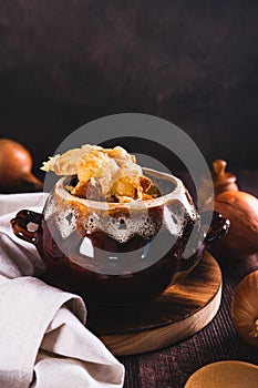 French onion soup with melted cheese and croutons in a pot on the table vertical view