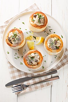French puff pastry Vol au vent filling with chicken, cream and mushroom closeup on the plate on the wooden table. Vertical top
