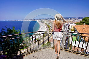 French Riviera. Back view of attractive young woman holding hat enjoying view of the cityscape of Nice, France