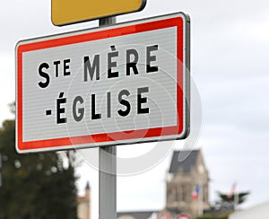 French road sign indicating the place where  the paratrooper hanging from the bell tower who fell during the Normandy landings