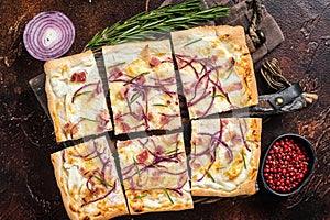 French tarte flambee with cream cheese, bacon and onions. Flammkuchen from Alsace region. Dark background. Top view