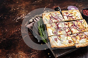 French tarte flambee with cream cheese, bacon and onions. Flammkuchen from Alsace region. Dark background. Top view