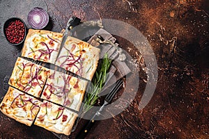 French tarte flambee with cream cheese, bacon and onions. Flammkuchen from Alsace region. Dark background. Top view