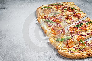 French tarte flambee with cream cheese, bacon, tomato and onions. Flammkuchen from Alsace region. White background. Top