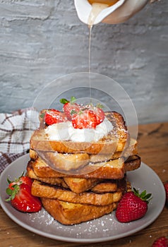 French toast with fresh strawberries, coconut shreds and dripping honey, on wooden background