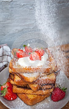 French toast with fresh strawberries, coconut shreds, honey and powdered sugar, on wooden background