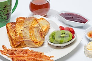 French toasts cooked and served with fruit, bacon, honey, jam and coffee