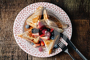 French toast served with syrup and fresh berries