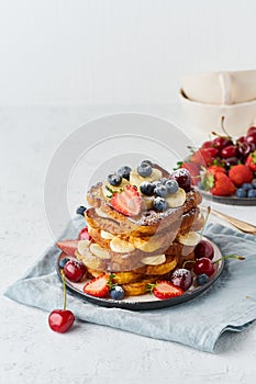 French toasts with berries and banana, brioche breakfast, white background vertical closeup