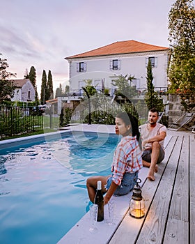 French vacation home with wooden deck and swimming pool in the Ardeche France. Couple relaxing by the pool with wooden