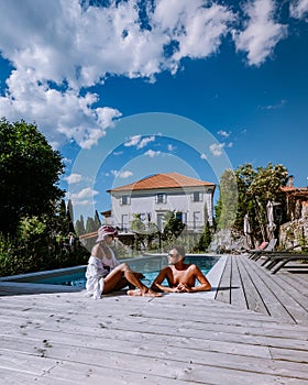 French vacation home with wooden deck and swimming pool in the Ardeche France. Couple relaxing by the pool with wooden