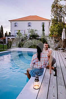 French vacation home with wooden deck and swimming pool in the Ardeche France. Couple relaxing by the pool with wooden