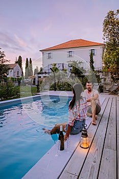 French vacation home with wooden deck and swimming pool in the Ardeche France. Couple relaxing by the pool with wooden