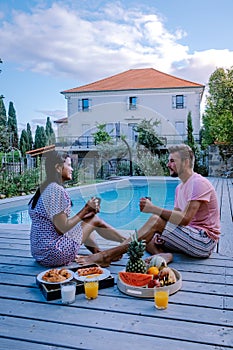 French vacation home with wooden deck and swimming pool in the Ardeche France. Couple relaxing by the pool with wooden