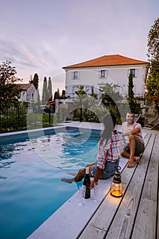 French vacation home with wooden deck and swimming pool in the Ardeche France. Couple relaxing by the pool with wooden