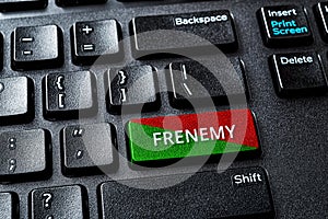 Frenemy word on the green red enter key of a desktop pc keyboard. Laptop computer enter key with warning message. Be an enemy