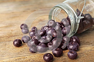 Fresh acai berries scattered from jar on table, closeup view. Space for text