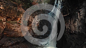 Fresh aerial scenery of water cascade with flowing stream from rock covered by plants