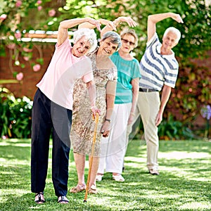 Fresh air and exercise is great for your health. a group of smiling seniors exercising outside.