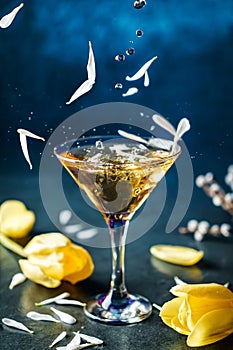 Fresh alcoholic cocktail with ice in martini glass on dark blue background. Studio shot of drink in freeze motion, flying ice and