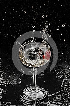 Fresh alcoholic cocktail with vodka, gin, ice, flower in wineglass on black background. Studio shot of drink in freeze motion,