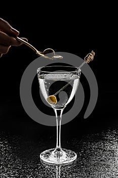 Fresh alcoholic cocktail with vodka and olive in wineglass on black background. Summer cold drink and cocktail