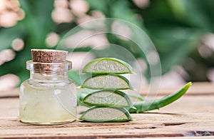 Fresh aloe leaves and aloe gel in the cosmetic jar on wooden table