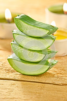 Fresh aloe vera slices on wooden with some candles.