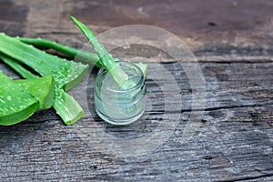 Fresh aloe vera stem slices and gel on wooden table, skin therapy concept