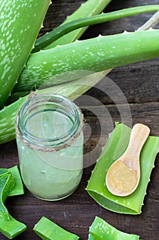 Fresh aloe vera stem slices and gel on wooden table, skin therapy concept