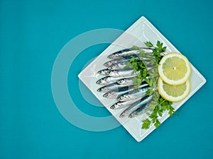 Fresh anchovies in a plate on a blue background