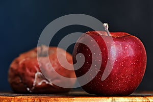 A Fresh Apple in the Foreground, A Rotten Apple Out of Focus In The Background. Good vs Bad. Antithesis Concept. Dark Background photo
