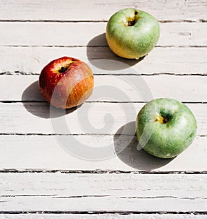 Fresh apples in the kitchen on the table, three apples. One red Apple and two green apples lie on a white wooden background