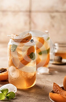 Fresh apricot cocktail, fizz or ice tea with mint and garnish. Pink beige tile background