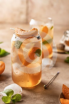 Fresh apricot cocktail, fizz or ice tea with mint and garnish. Pink beige tile background