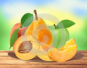 Fresh apricot, peach, apple and pear on wooden plate over nature