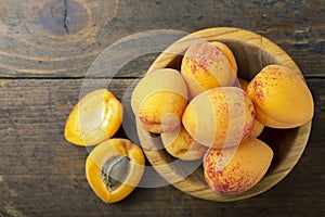 Fresh apricots in a wooden plate. Fruits are scattered on a wooden table
