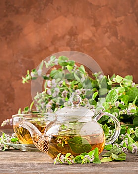 Fresh aromatic tea with melissa mint leaves glass teapot on a rustic background. Healing herbal drink. Vertical frame.