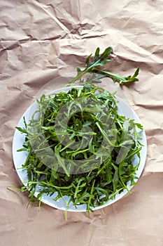 Fresh arugula Eruca, a cruciferous plant, and simply cabbage Brassicaceae on brown wrapping kraft paper.