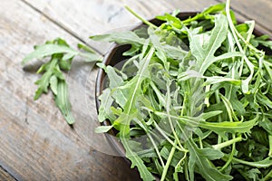 Fresh arugula leaves in a bowl on a wooden table